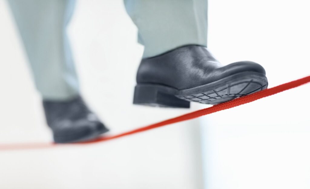Business man walking a red tight rope